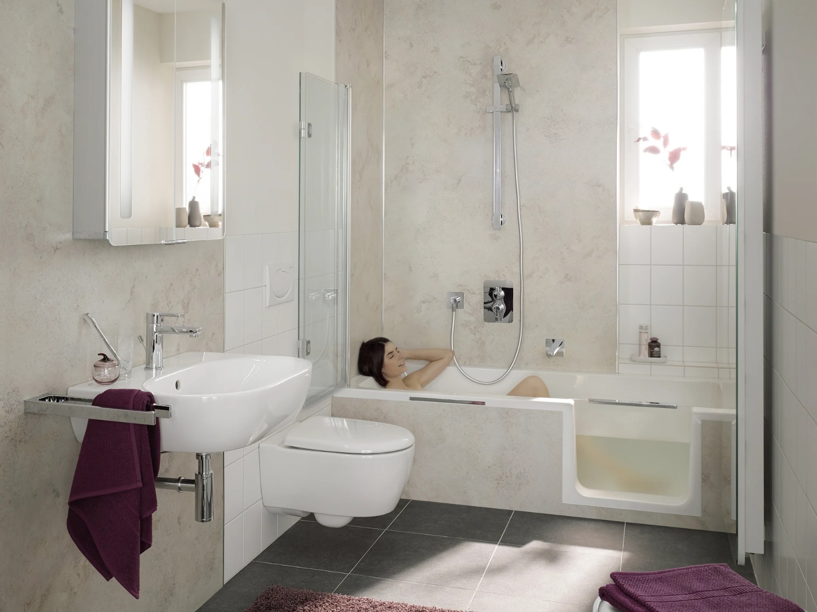 Lichte badkamer met marmerlook wanden, ligbad met instap en hangend toilet